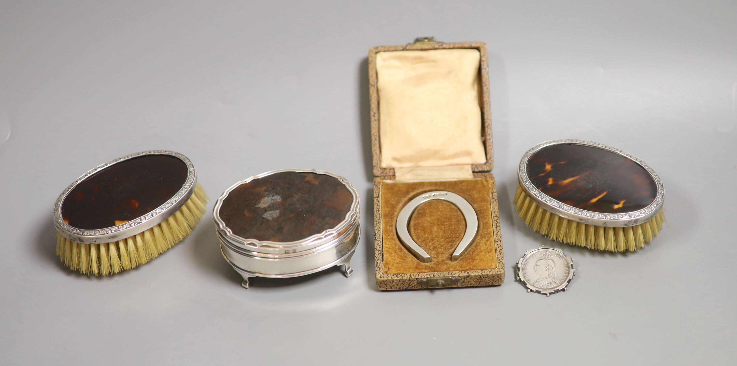 A George V silver and tortoiseshell mounted trinket box, brushes, horseshoe and brooch.